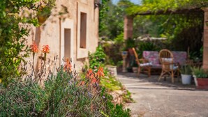 Un bâtiment rustique en pierre, avec un jardin à l’avant, où l’on peut admirer une grande variété de plantes et de fleurs.