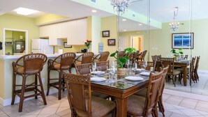 Un coin repas avec une table en verre, des chaises en osier et un lustre.
