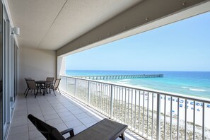 A balcony with a view of the beach and a pier.
