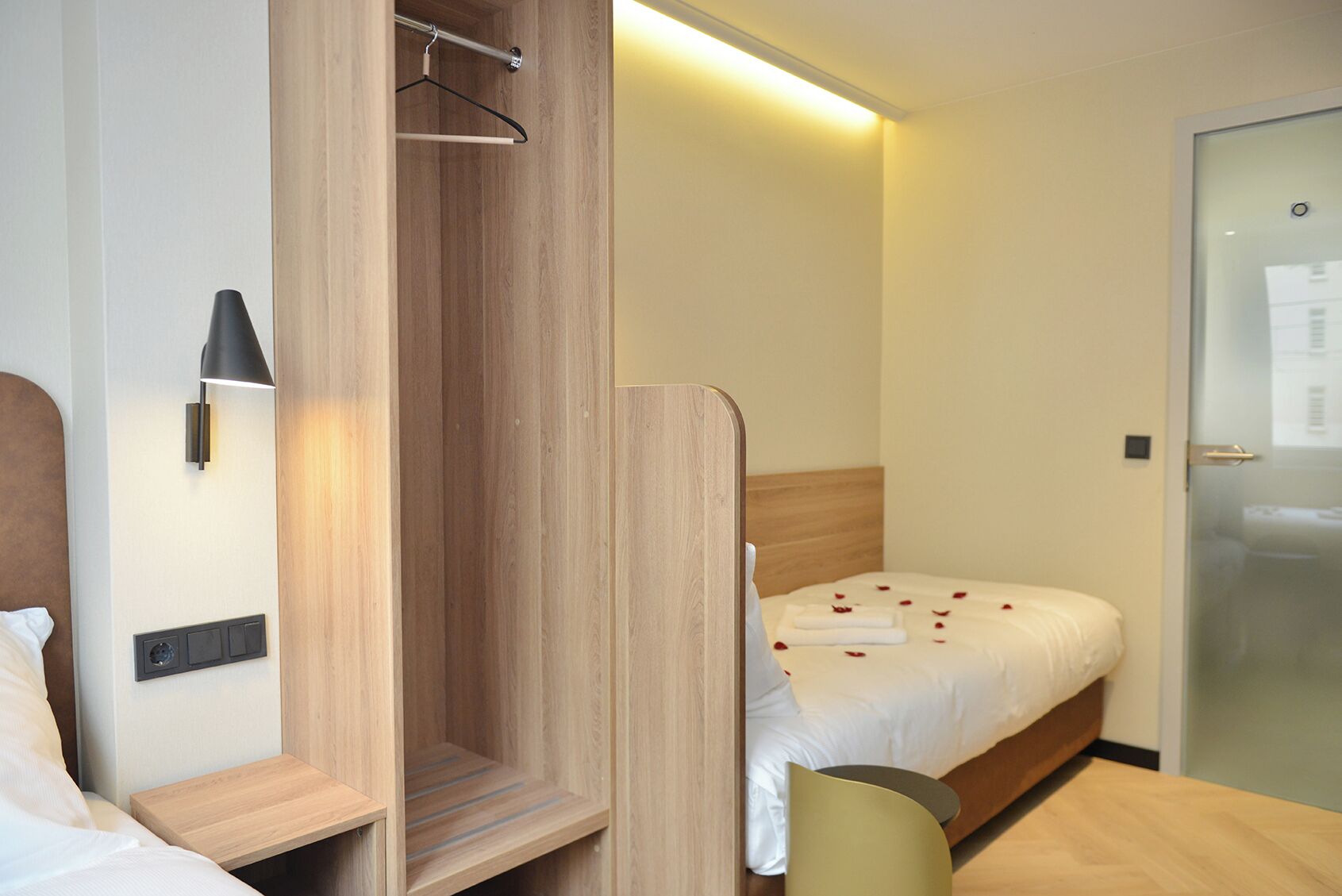 Ein Hotelzimmer mit einem Holzschrank, einem Bett mit Rosenblättern, einem Nachttisch und einem Sessel.