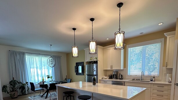 A modern kitchen with a central island, bar stools, and pendant lighting. - Serene Farm Stay (Nanaimo)