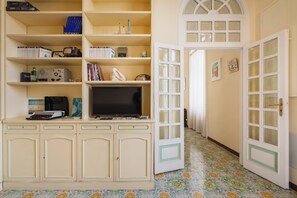 Ein Zimmer mit Fernseher, Büchern und einem Schreibtisch mit Computer.