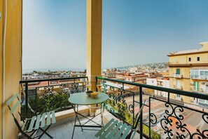 A balcony with a table, chairs, and a view of the cityscape. - CasaChi | View of Capri, a balcony, and charm in the heart of Chiaia—Naples (Napoli)