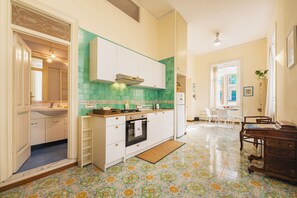 Eine moderne Küche mit weißen Schränken, einer grünen Spritzschutzleiste und einem gefliesten Boden mit floralen Mustern.