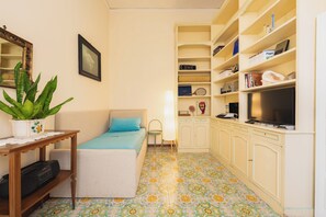 Ein kleines Zimmer mit einem Bett, einem Schreibtisch, einem Fernseher und einem Bücherregal.