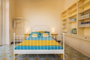 Ein Schlafzimmer mit einem Bett, Nachttischen, einem Bücherregal und einem gemusterten Boden.