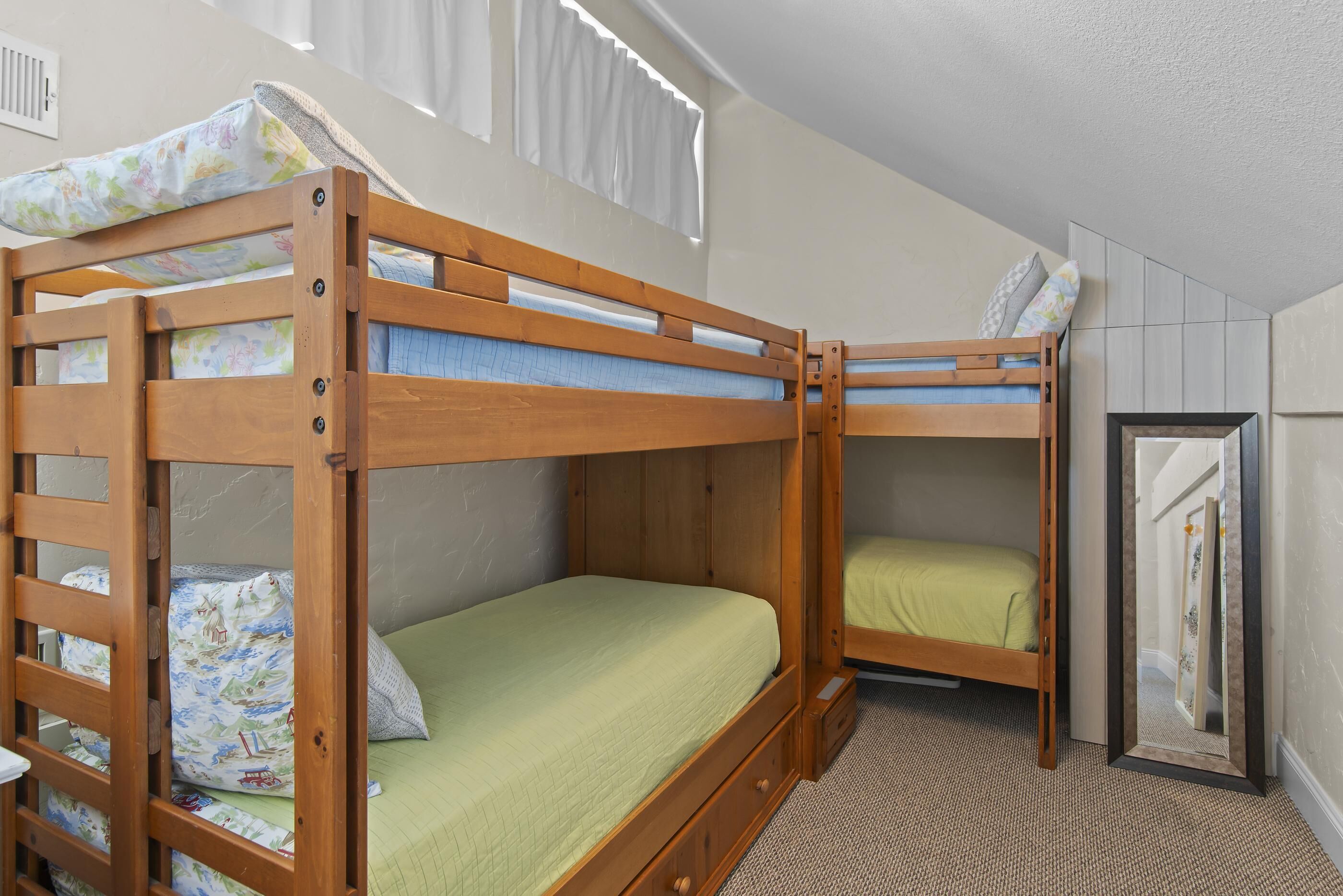 A bunk bed room with a window, a wardrobe, and a mirror.