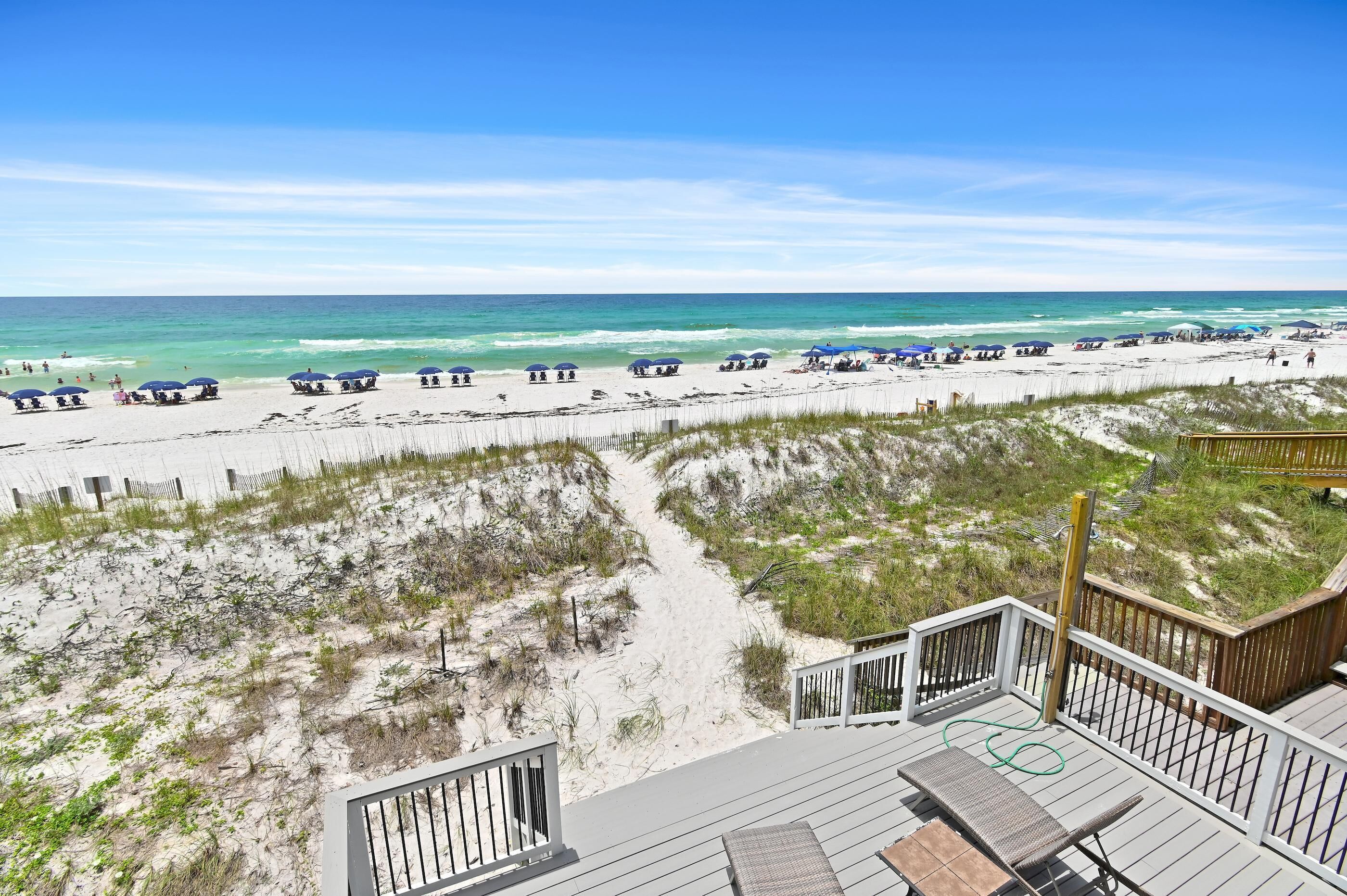A beach view with a wooden deck and beach umbrellas.