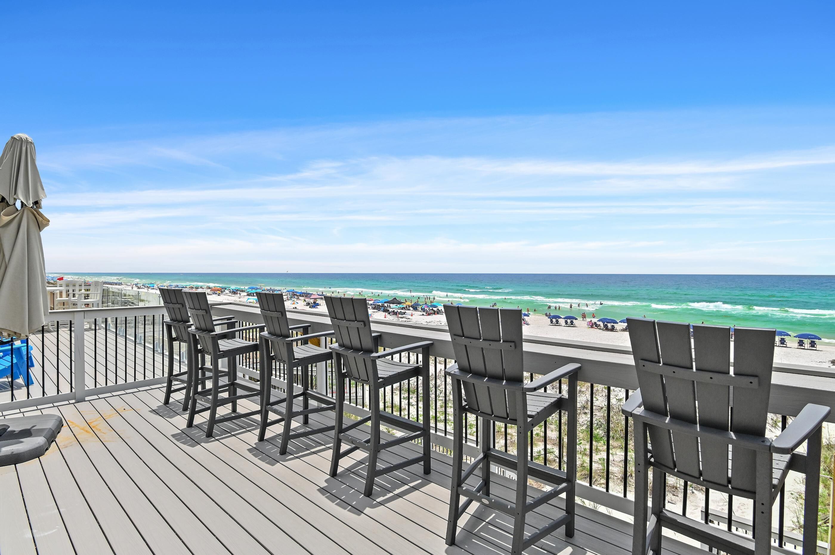 A deck with chairs overlooking a beach.