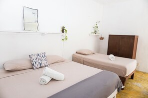 Ein Zimmer mit zwei Betten, einem Spiegel und einem Holzschrank.