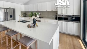 Een moderne keuken met witte kasten, een roestvrijstalen koelkast en een centraal eiland met krukken.