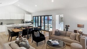 Een moderne woonkamer met een bank, salontafel en een eethoek met tafel en stoelen.
