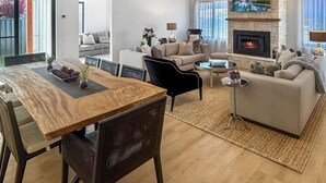 Een moderne woonkamer met een open haard, een eethoek met een houten tafel, en een zithoek.