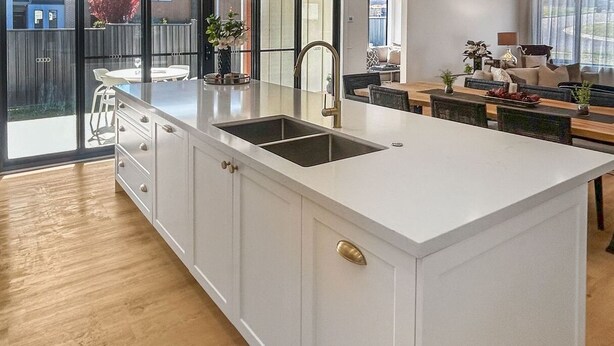 Een moderne keuken met een groot eiland, witte kasten en een inbouwspoelbak.