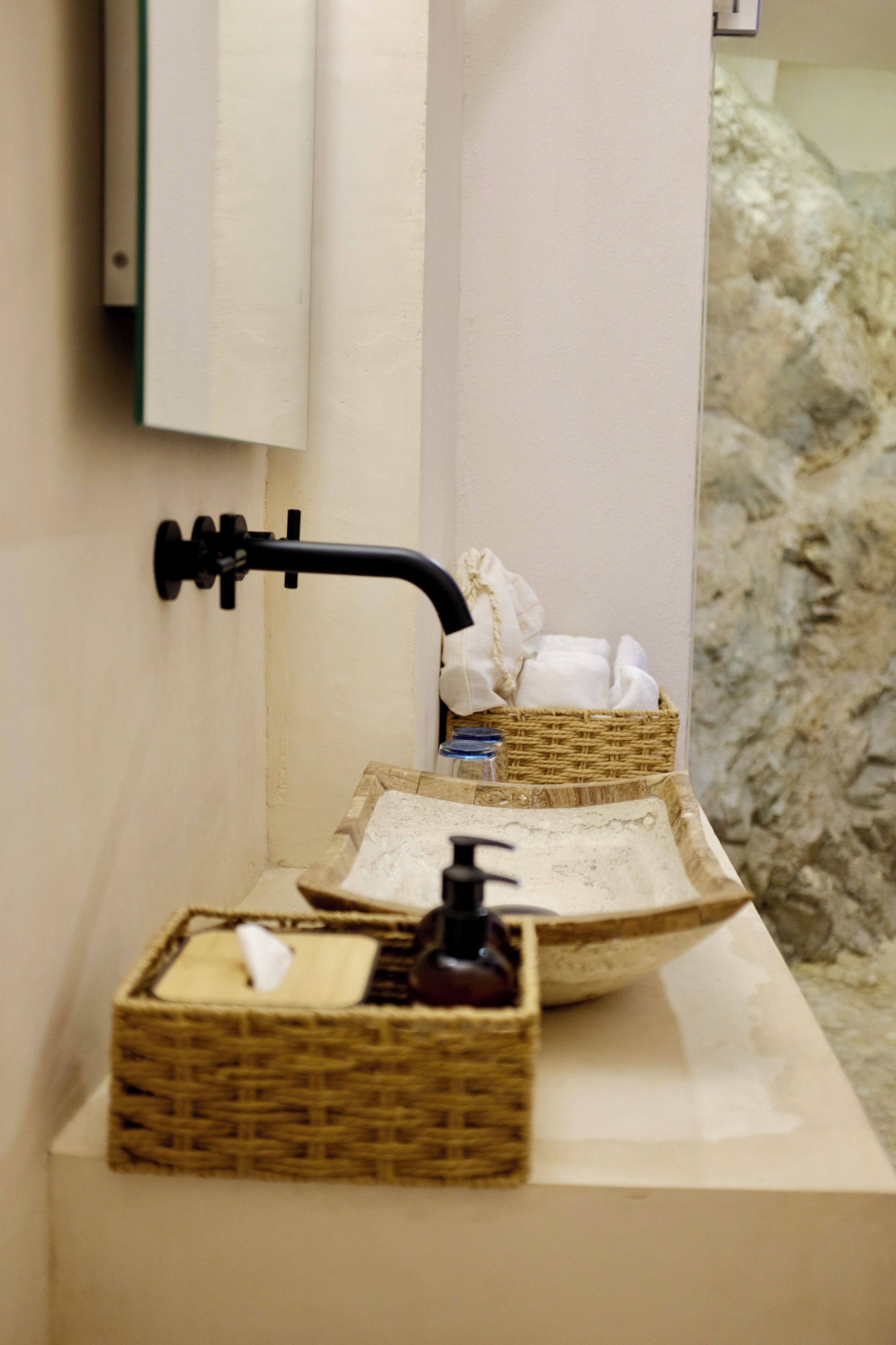 A bathroom with a white sink, a black faucet, and two wicker baskets on the counter.
