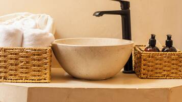 A bathroom with a beige sink, black faucet, and two wicker baskets on the countertop.