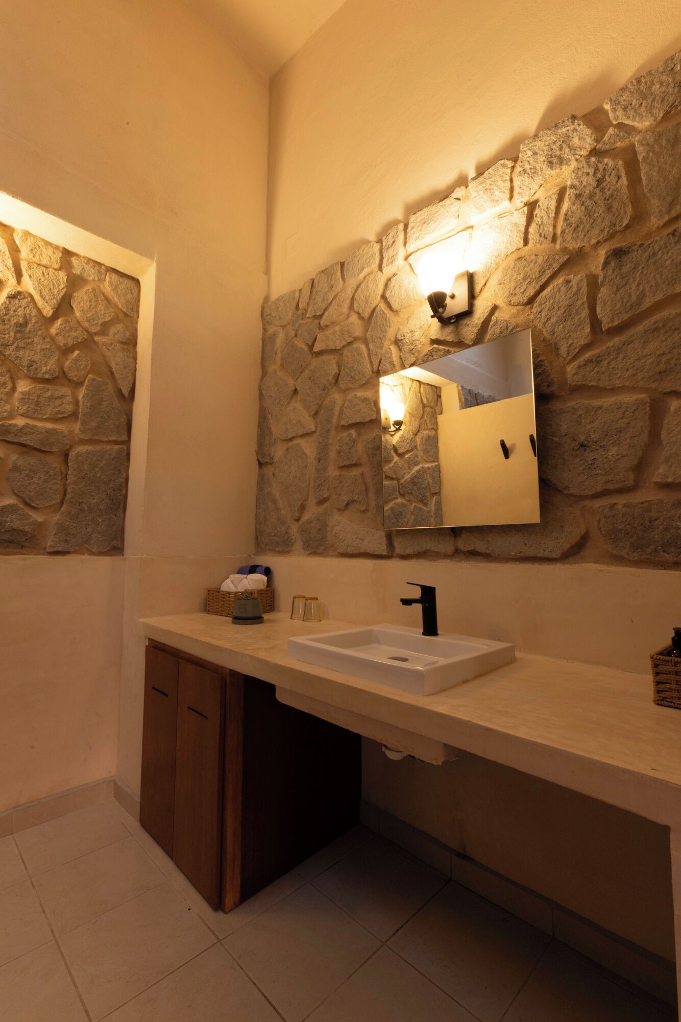 Une salle de bain avec un mur en pierre, un lavabo et un miroir.