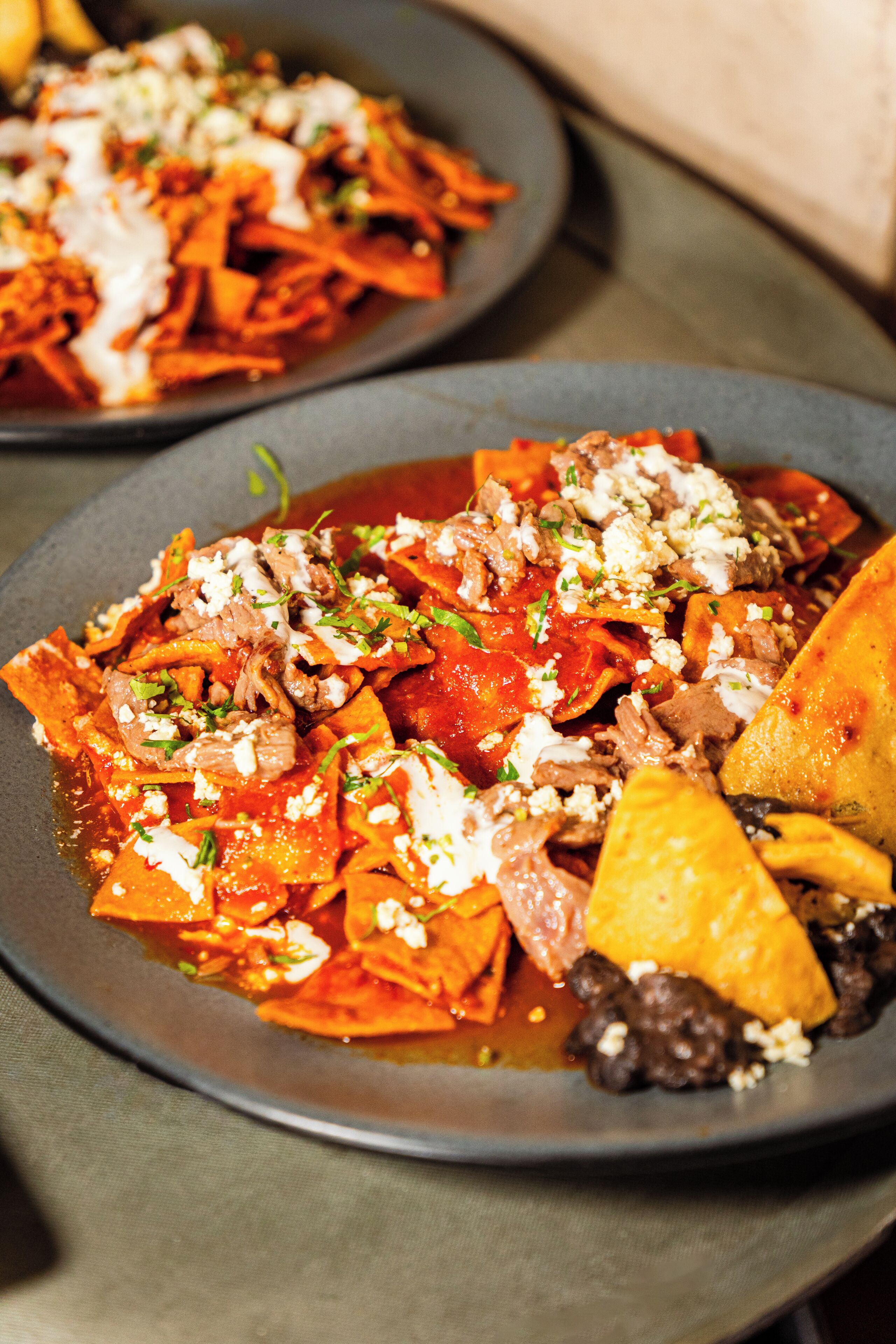 Um prato de nachos com queijo, carne e legumes.