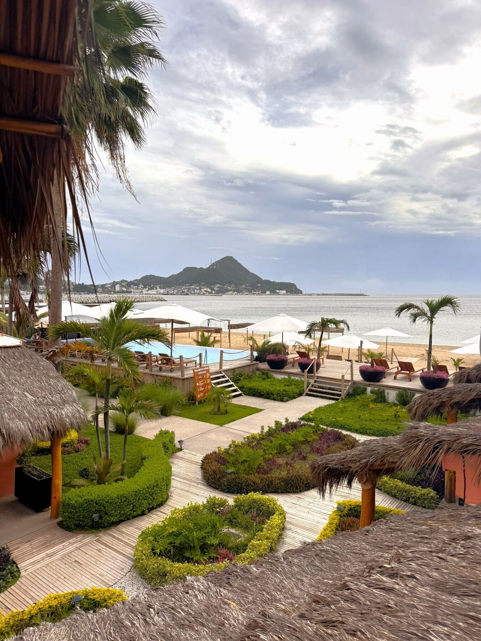 A resort with a pool, lounge chairs, and a view of the ocean.