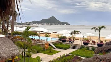 Un resort con piscina, sillas de descanso y vista al océano.