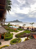 Un resort con piscina, sillas de descanso y vista al océano.