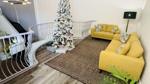 A modern living room with a staircase, a yellow sofa, and a Christmas tree. - Clarion Pointe (Albemarle)