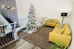Una sala de estar moderna con una escalera, un sofá amarillo y un árbol de Navidad.