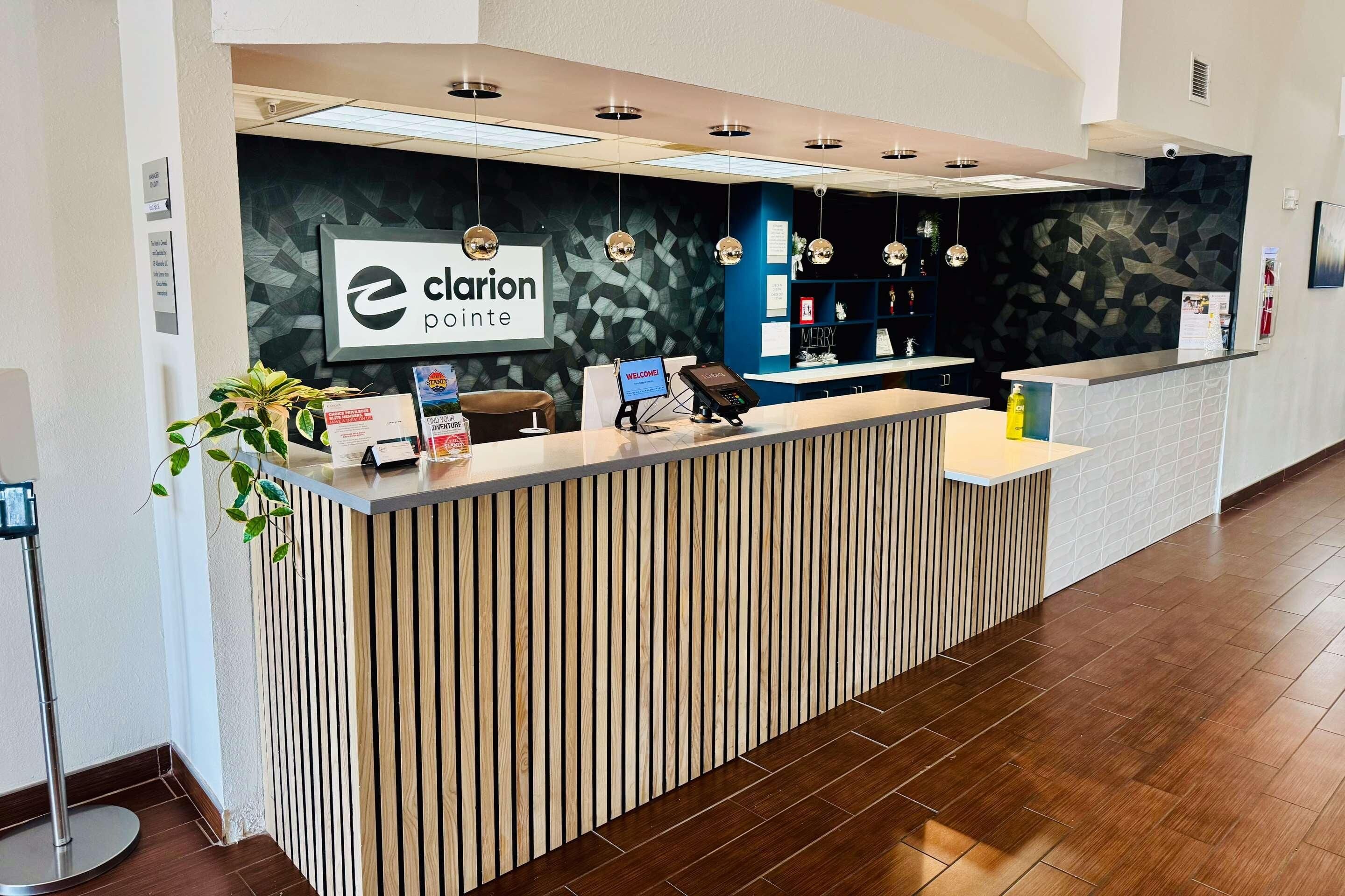 A reception desk with a 'Clarion Pointe' sign, a computer, a phone, and a plant.