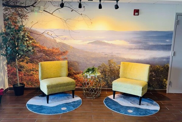 Una habitación con dos sillones amarillos orientados hacia un gran mural que representa un paisaje montañoso.