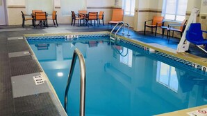 A swimming pool with a clear blue water, a pool ladder, and a seating area with chairs. - Clarion Pointe (Albemarle)