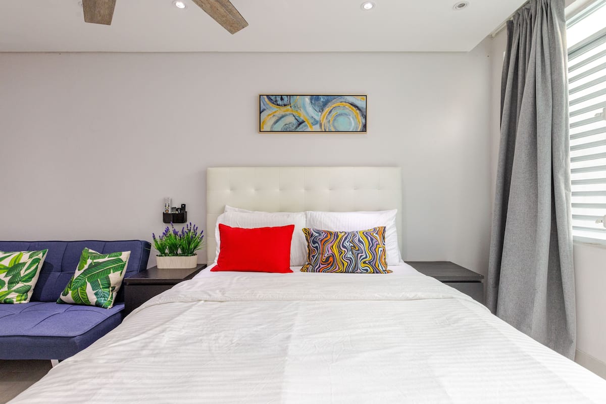 Un dormitorio moderno con una cama grande, un sofá y una mesita de noche.