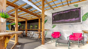 An indoor patio with wooden pergola, seating, and potted plants. - City Beach Apartments (San Juan)