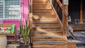 A wooden staircase leading to a room with a sign indicating "ROOM 2". - City Beach Apartments (San Juan)