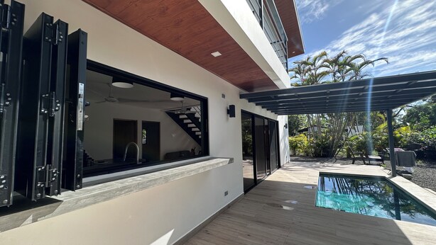 A modern house with a large window, a wooden deck, and a swimming pool.