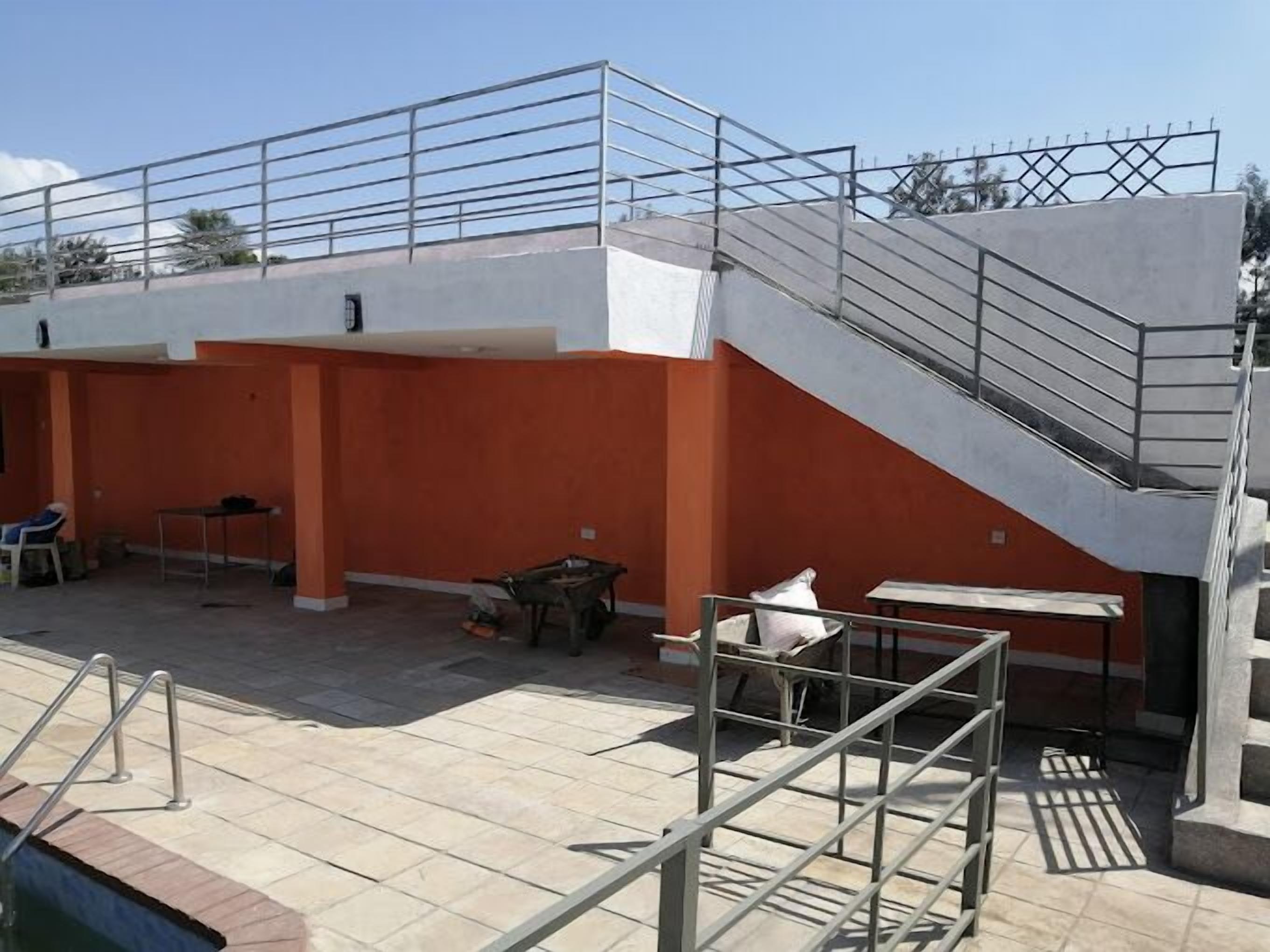 A rooftop terrace with a staircase, outdoor seating, and a pool area.