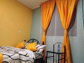 Quarto com cama, almofadas amarelas e cortinas laranjas.