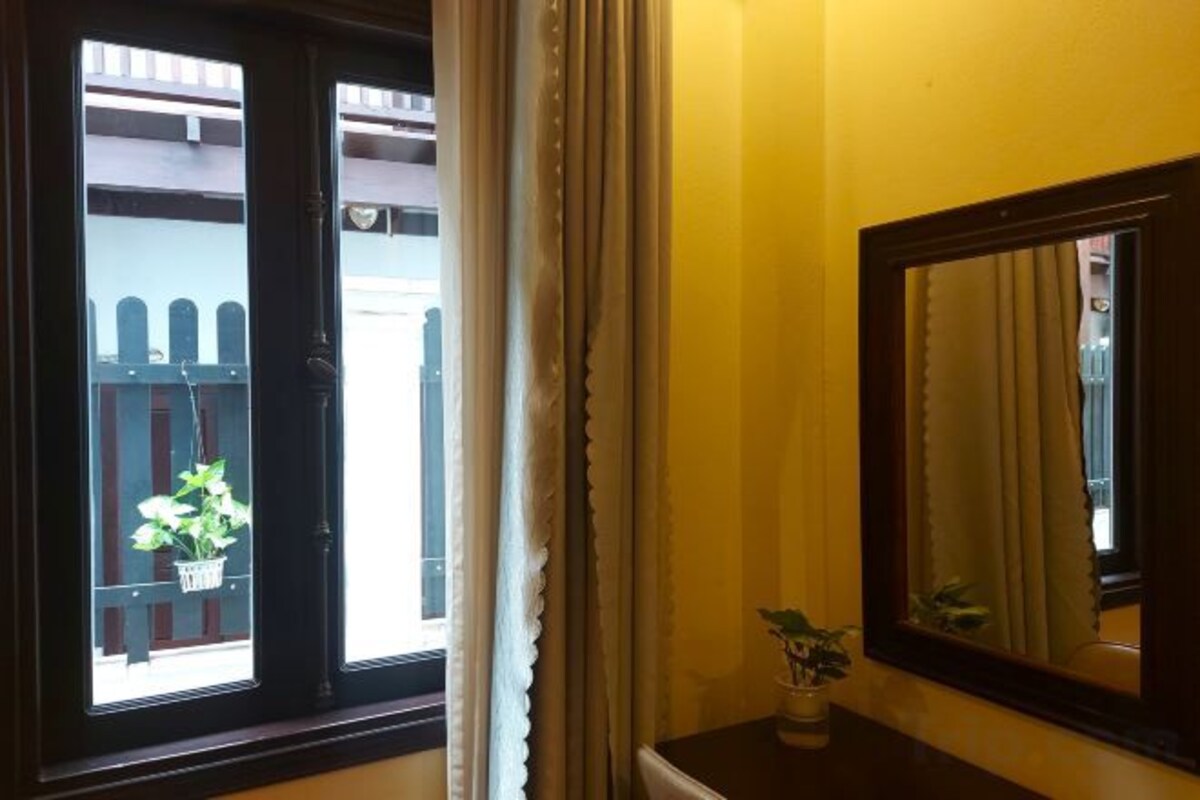 Une pièce avec une fenêtre, un miroir et une plante en pot.