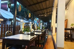 Un restaurant en plein air avec des tables et des chaises, une allée couverte et une vue sur la rue.