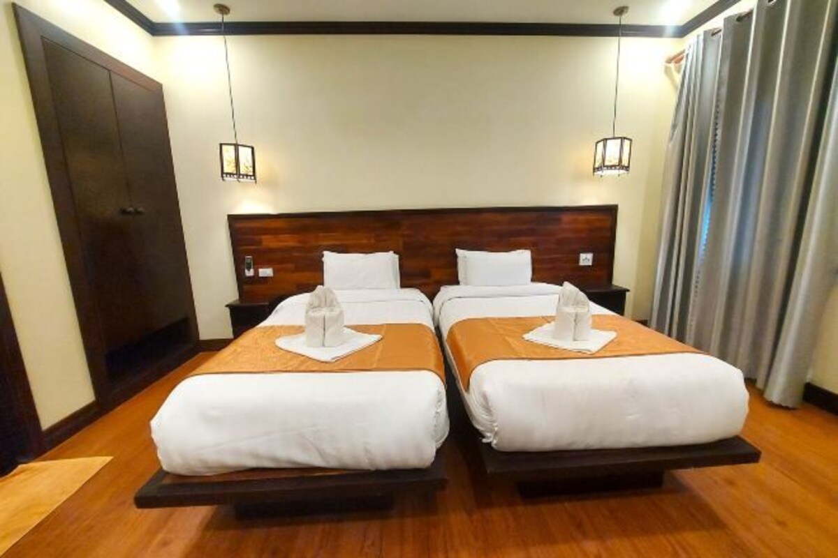 A hotel room with two beds, wooden headboards, and bedside lamps.