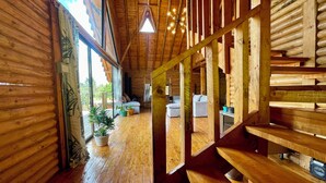 A wooden interior with a staircase, large windows, and a ceiling light fixture.