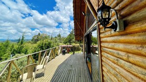 A wooden deck with a railing, a chair, and a lantern.