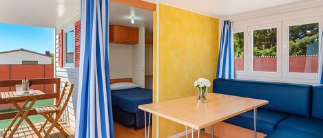 Una habitación con una mesa de madera, un sofá azul, una cama y un ventanal con cortinas.