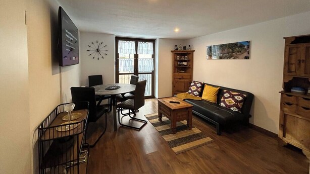 Un salon comprenant une table à manger, des chaises, un canapé et un meuble en bois.