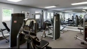 Een sportschool met diverse fitnessapparaten, waaronder krachttoestellen en losse gewichten.