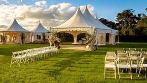 Un espace événementiel extérieur aménagé avec des tentes, où des chaises blanches sont disposées pour accueillir les participants.