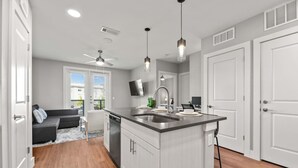 A modern kitchen with a central island, built-in dishwasher, and a ceiling fan. - Luxury King 1bd Pool + Gym + Parking + Stockyards (Fort Worth)