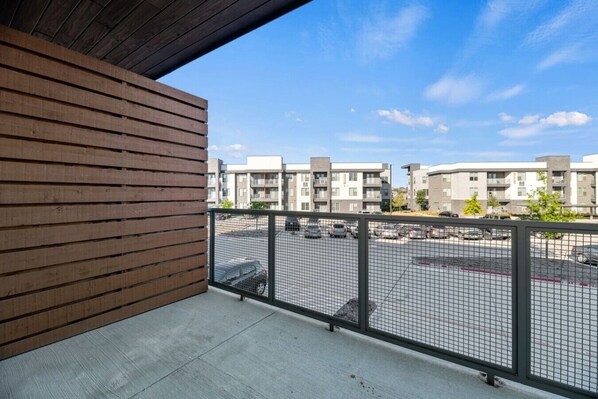 A balcony with a view of a parking lot and residential buildings.