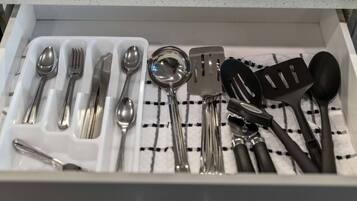 A drawer containing various kitchen utensils including spoons, forks, a spatula, and a ladle.