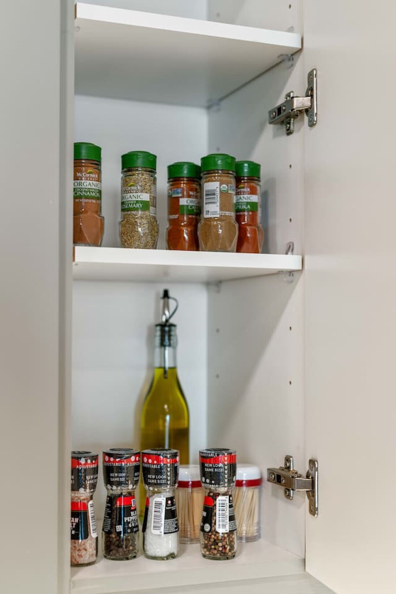 Un armario de cocina con frascos de especias y una botella de aceite de oliva.