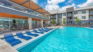 Een modern hotel met een zwembad, ligbedden en een overdekt terras.